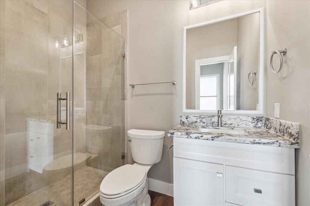 Stylish and practical, this secondary bath features a granite vanity, spacious walk-in shower, and neutral tile finishes that complement the home’s modern design.