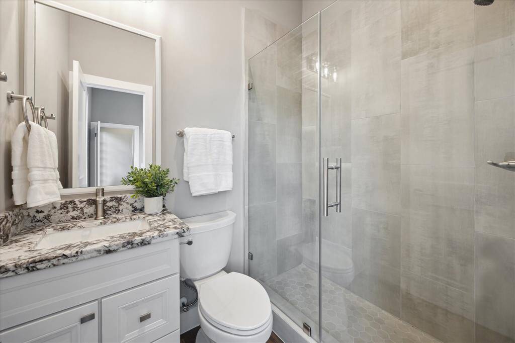 Sleek fixtures, a frameless glass enclosure, and a rich stone countertop elevate this private bath with a refined, contemporary feel.