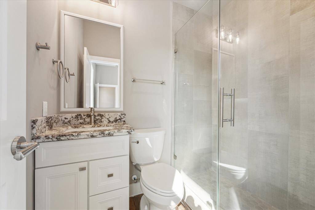 This private full bath features sleek finishes, a granite-topped vanity, and a spacious walk-in shower—ideal for guests, roommates, or anyone using the first-floor flex suite.