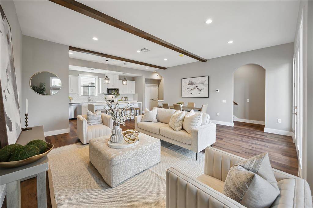Wood ceiling beams add warmth and architectural flair to this modern open-plan living space, where the living, dining, and kitchen areas flow effortlessly together—perfect for hosting or everyday comfort.
