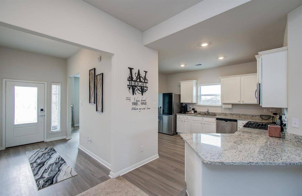 The modern kitchen connects the open layout to a bright entryway, dining room, and flow into the large living room creating a welcoming atmosphere.