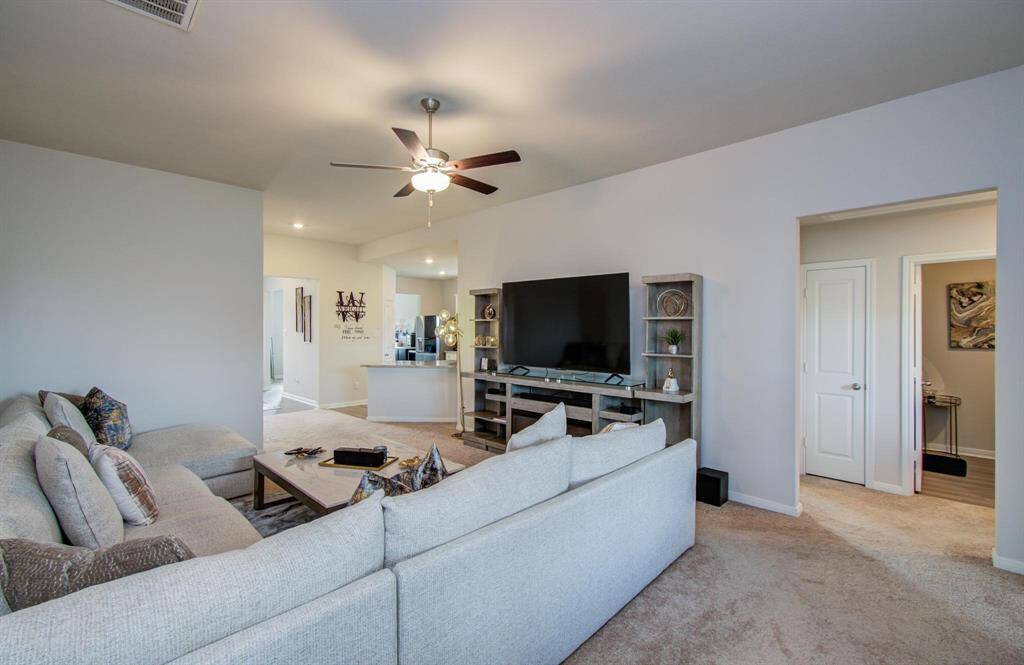 The living room is connected to a well-lit hallway, secondary bedrooms and full bath, and has an adjacent primary bedroom entrance. Modern decor and carpeted flooring enhance the inviting atmosphere.