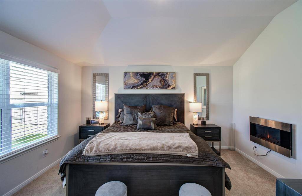 This primary bedroom is spacious with room for a large bed, two bedside tables and a dresser while the large window allows natural light to fill the room.