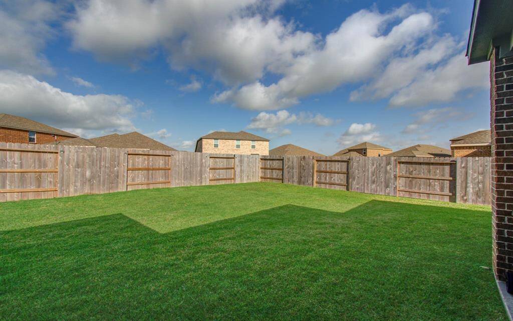 Spacious backyard with well-maintained green lawn, surrounded by a wooden privacy fence. Ideal for outdoor activities and relaxation.