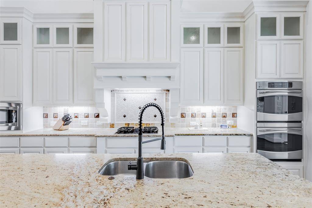 This impeccable kitchen is a showstopper! Featuring custom cabinetry with glass accents, an enormous kitchen island with breakfast bar and recessed lighting.