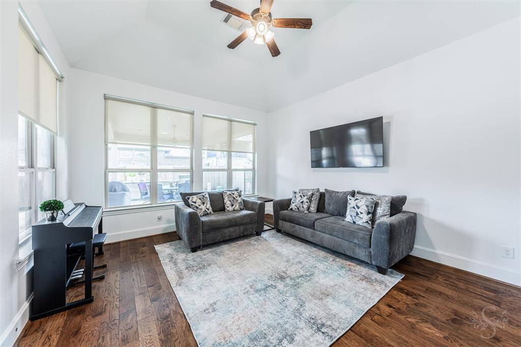 Bright and airy game room with high ceilings, hardwood floors, ceiling fan and large windows. Any game room furniture or gamer table will fit just right in a space like this.