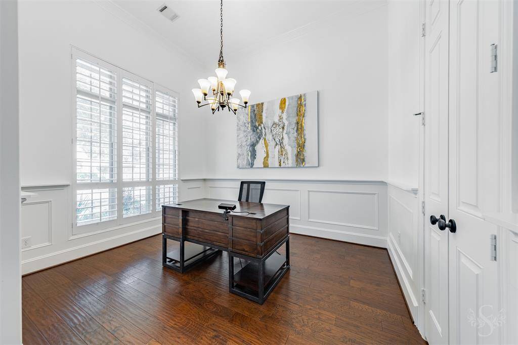 The formal dining room, left  of the front door entry features a wall of windows to filter natural light gently, wood flooring, wainscoting and an entrance to the butler pantry.