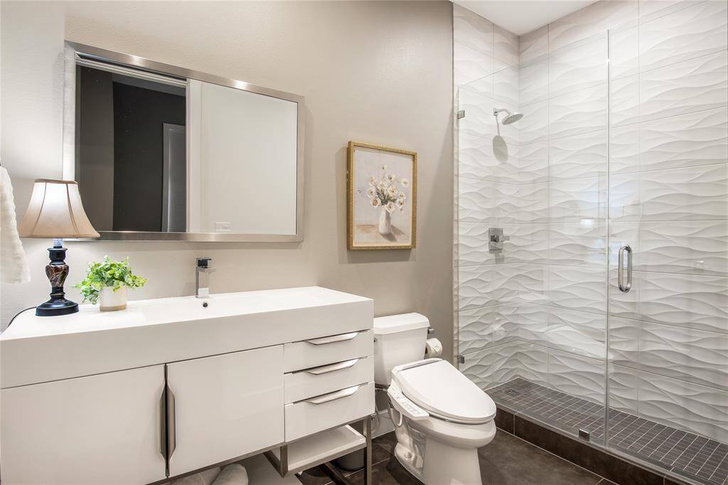 En suite bathroom in the secondary bedroom has a large vanity, lots of storage and a beautiful large walk-in shower.