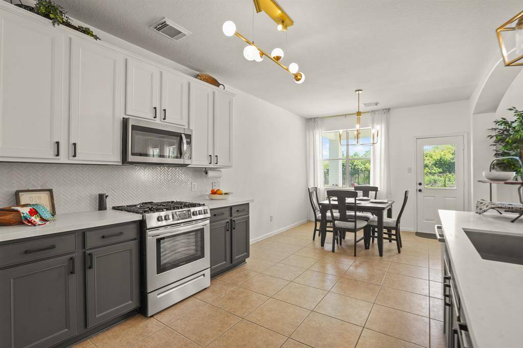 Elegant quartz countertops and a stylish herringbone backsplash enhance the kitchen's modern appeal.