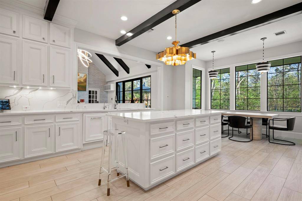 Chefs kitchen featuring a large island with lots of cabinets, designer lighting beams and a walk-in pantry.