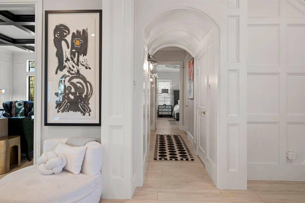 Downstairs off the foyer to the right is a beautifully arched hall with designer wall sconces leading you to the primary suite.