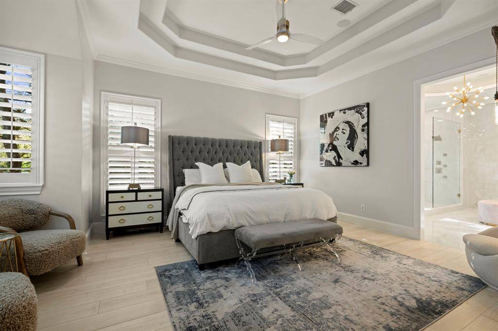 Generously sized primary suite featuring plantation shutters, designer ceiling fan and a sitting area along the bay windows