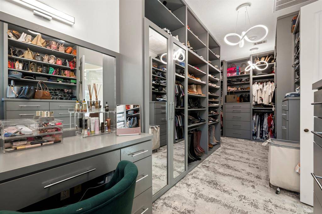 View of the closet with lots of custom cabinetry and a vanity