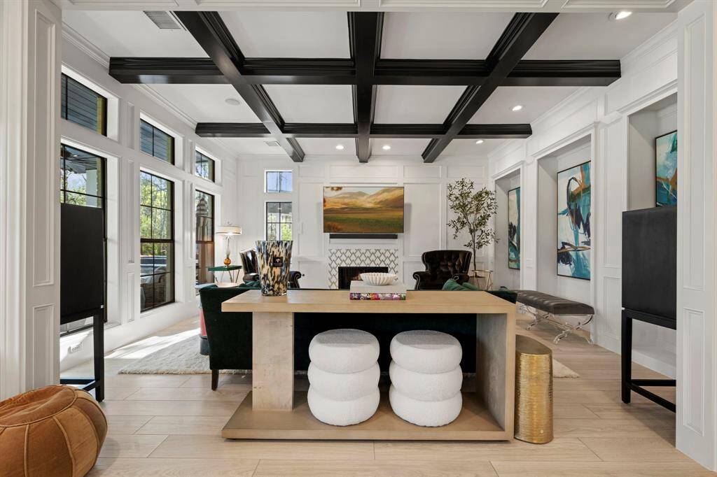 Formal living room featuring a fireplace, beams, wall paneling and a gallery wall complete with art lighting