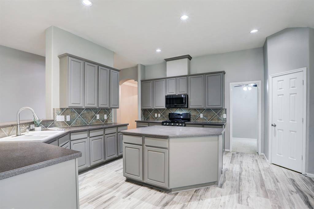 This modern kitchen features double sinks and a stylish tile backsplash, perfect for culinary enthusiasts.