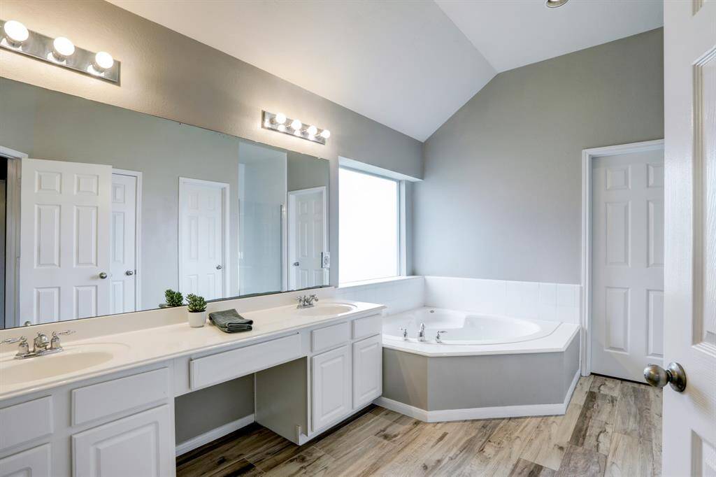 Luxurious bathroom featuring double sinks, a whirlpool tub, and a separate shower. Two updated mirrors have been installed as well as updated light fixtures since this photo was taken.