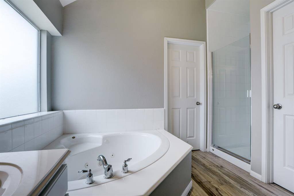 View of whirlpool tub, separate shower, door to walk-in closet and the nearest door is to toilet area...