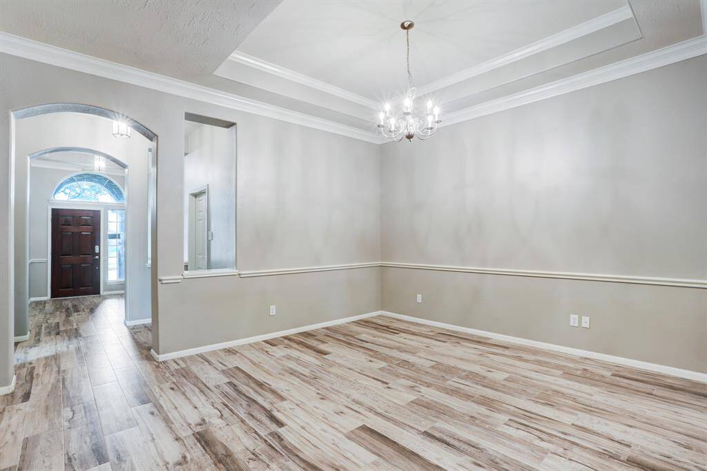 Formal dining room featuring a tray ceiling and porcelain wood-look floors—perfect for entertaining.