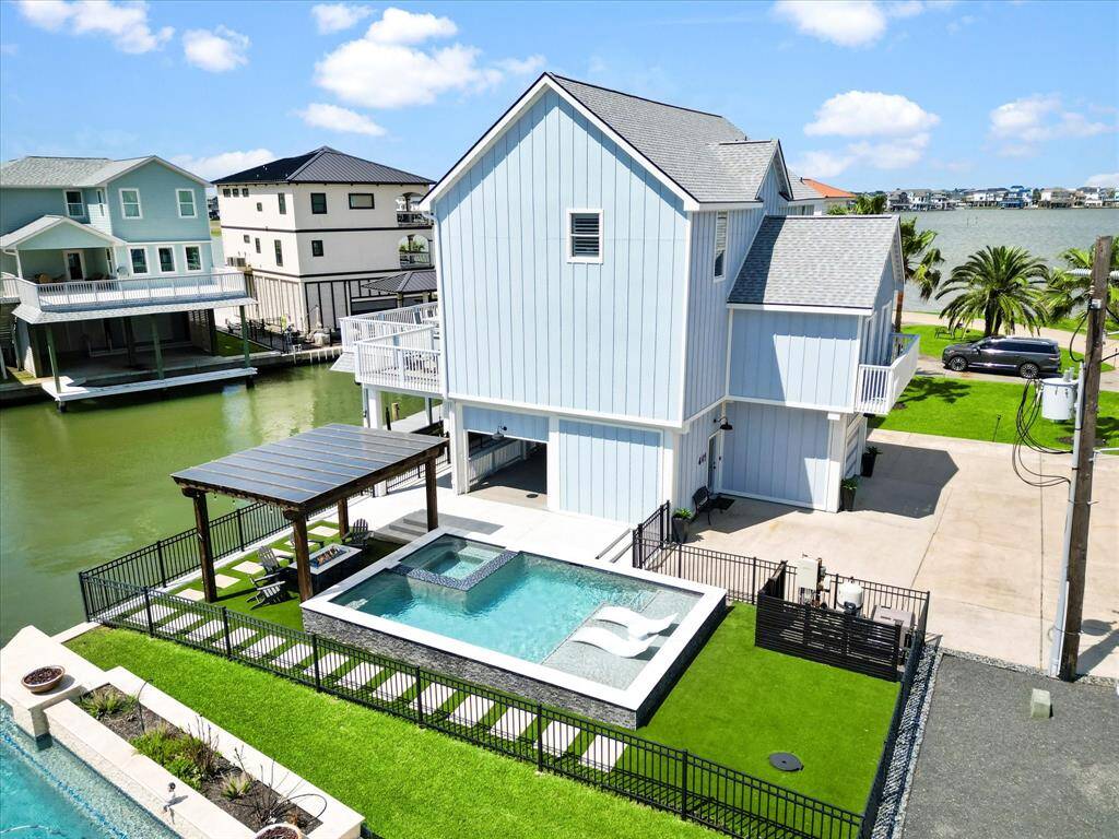This waterfront property features a modern, multi-level home with a sleek design and large windows. It includes a private pool, a spacious deck with a pergola, and direct access to a canal. Ideal for enjoying serene water views and outdoor living.