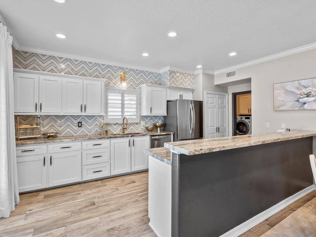 This kitchen features modern cabinetry with a stylish chevron backsplash, stainless steel appliances, and ample counter space. The open layout and sleek design offer a bright and inviting atmosphere, perfect for cooking and entertaining.