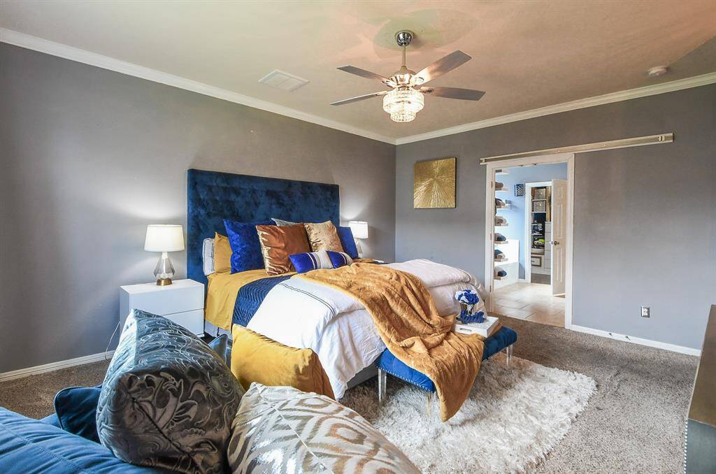A flash of color spices up your primary ensuite bath, creating a pleasing visual with deep toned cabinetry, topped by durable granite, framed wall-wide mirror and delicate modern lighting, above.