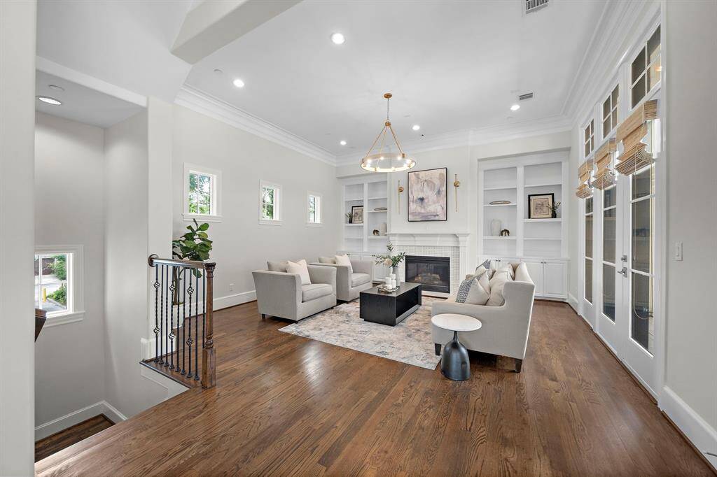 The open-concept living space is highlighted by soaring ceilings, designer chandelier, and hardwood floors, offering abundant natural light through multiple windows.