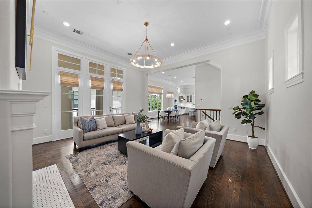 Sophisticated living area seamlessly connects to the open-concept kitchen and dining spaces, featuring rich hardwood floors, soaring ceilings, and abundant natural light.