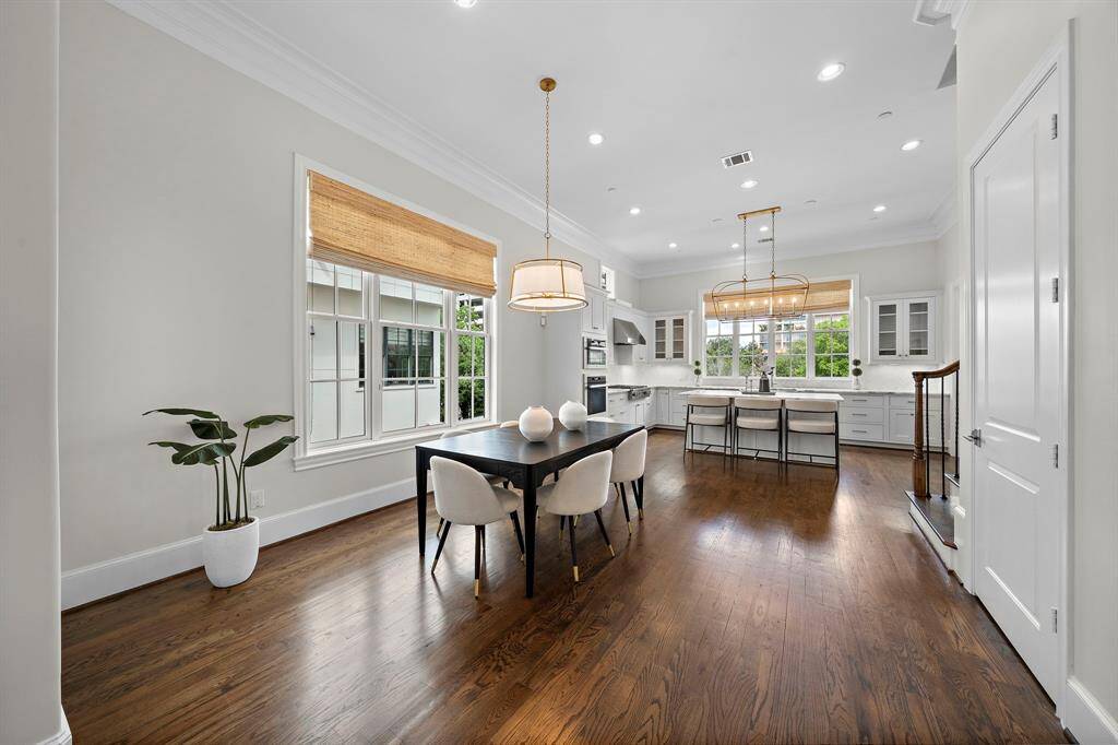 Formal dining area features wide-plank hardwood floors, crown molding, and a stunning designer light fixture that anchors the room. Abundant natural light streams in through large windows, while built-in display cabinetry and seamless flow to the chef’s kitchen create an entertainer’s dream setting for sophisticated gatherings.