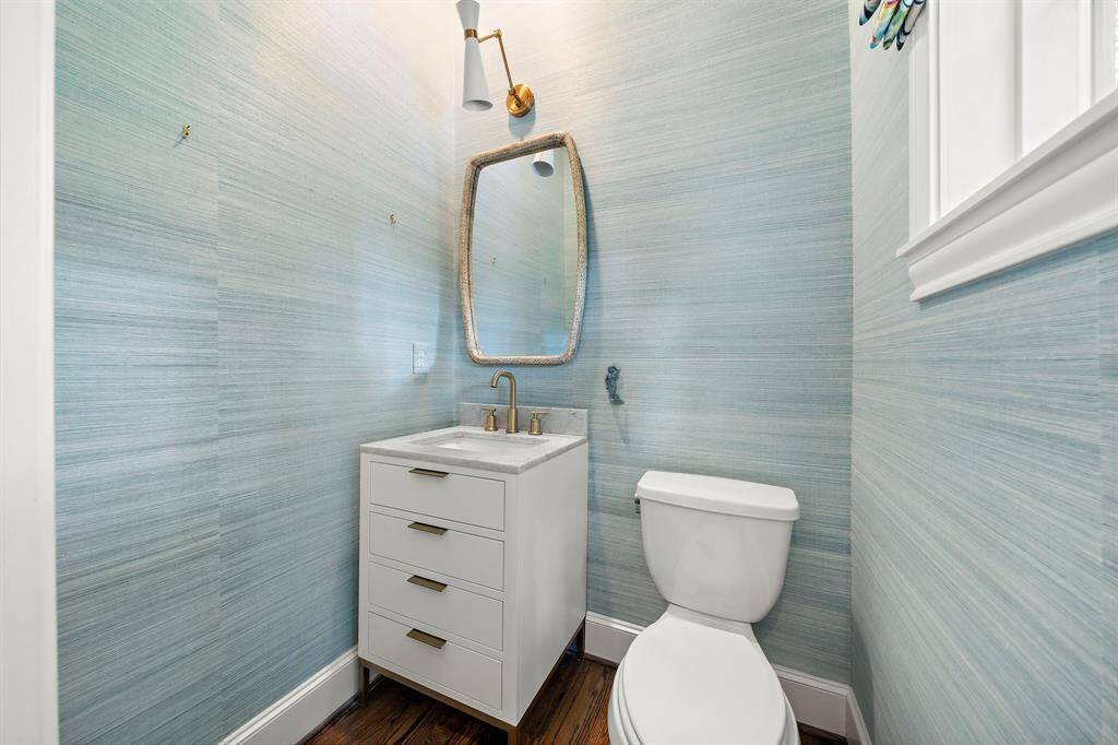 The updated half bath dazzles with marble countertops, striking brass fixtures, and a sleek modern vanity. Designer wallpaper and contemporary lighting create an upscale boutique feel, while thoughtful details elevate every guest visit in this luxury residence.