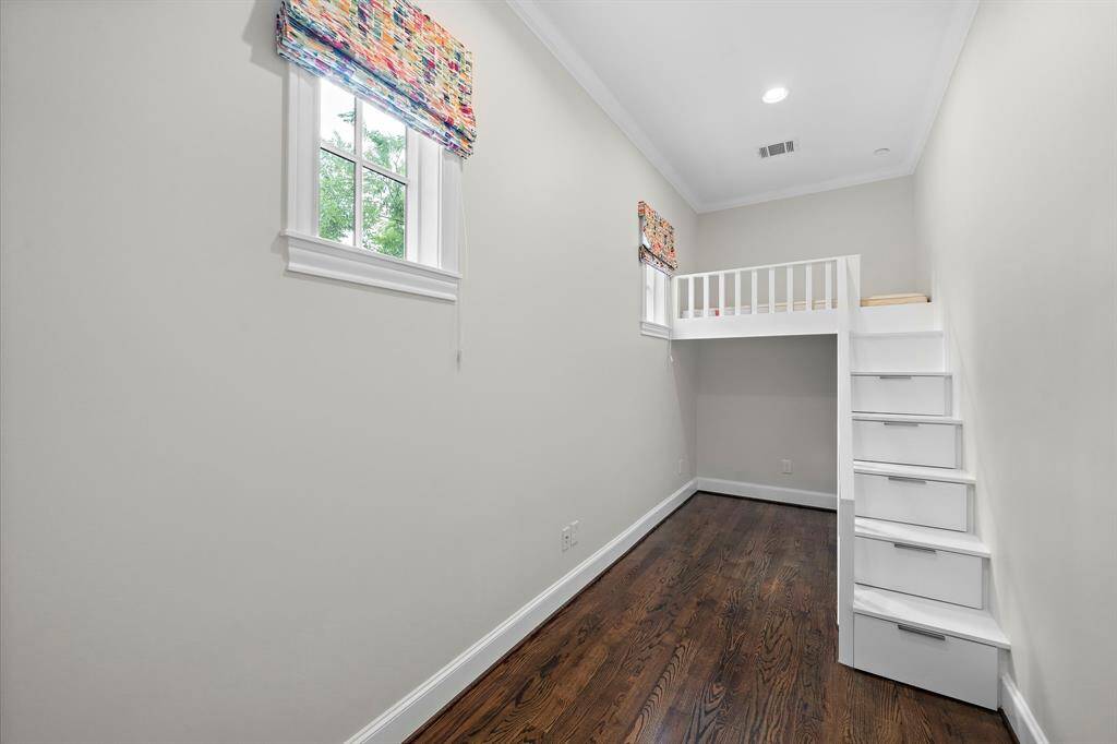 Flexible secondary room features rich hardwood floors, soaring ceilings, and a custom-built loft with storage drawers built into the staircase. Large windows with bold designer shades provide abundant natural light, making this space well-suited for a study, creative zone, or stylish private retreat.