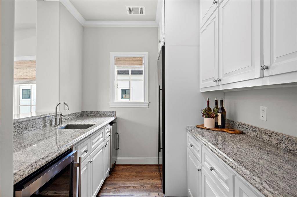 Experience elevated utility with this dedicated laundry and mud room, featuring custom built-in cabinetry, granite countertops, and a sleek under-counter beverage fridge.