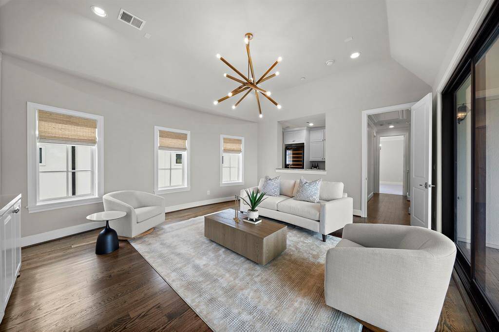 Sophisticated game room showcases accent lighting, hardwood flooring, and an open layout ideal for entertaining. Enjoy wet bar with beverage fridge, private balcony access, and large windows that flood the space with gentle natural light for a refined retreat.