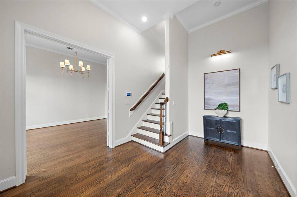 The soaring foyer welcomes you with crisp crown molding, wide-plank hardwood floors, and elevated ceilings, showcasing refined luxury from the moment you enter.