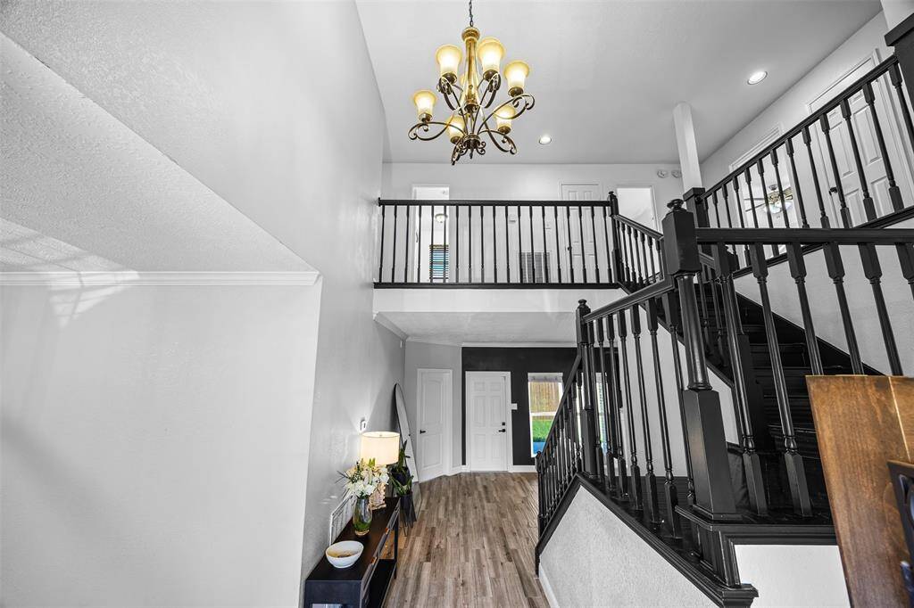 Striking two-story entry with modern black staircase, elegant chandelier, and open flow into a sleek white kitchen with breakfast bar seating. The updated kitchen is a chef’s dream with ample cabinetry, granite countertops, and a cozy breakfast nook overlooking the peaceful backyard. Step outside to a private patio ideal for grilling, relaxing, or future outdoor upgrades.