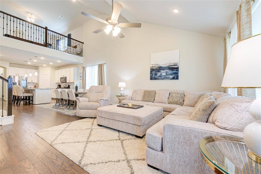 Bright living room with high ceilings, neutral decor, and hardwood floors.