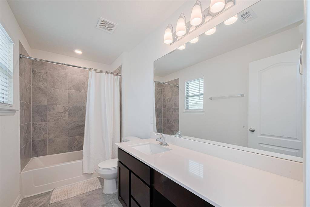 The Spacious Bathroom has a Large Vanity with Modern Lighting and even a Recessed LED light above the Tub / Shower combo with a Window allowing for Natural Light.