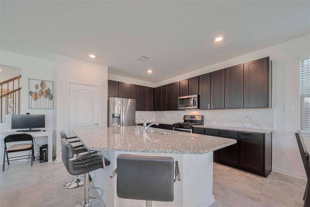 This is the kitchen the home chef has been dreaming of featuring a Large Island with a Breakfast Bar, Granite Countertops, Tiled Backsplash, Gas Range, Stainless Steel Appliances and a Large Walk-In Pantry.