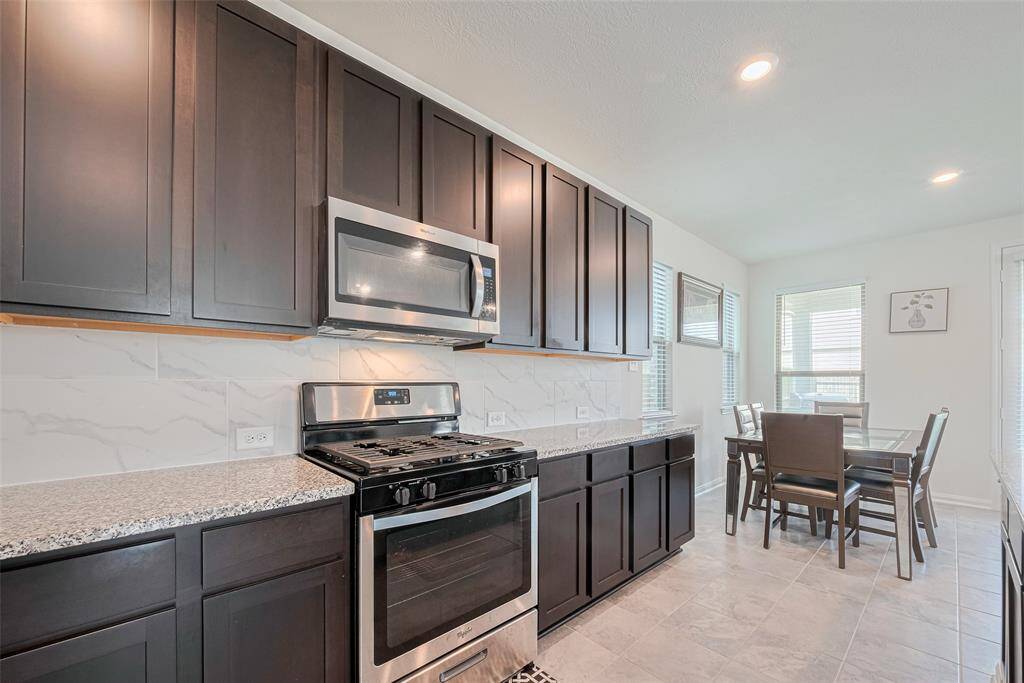 There is So Much Storage and plenty of Counter Space to get assistance from your little sous chefs in training. The Dark cabinets are complemented by the Light Colored Marble Look Tiled Splash and Granite Countertops.