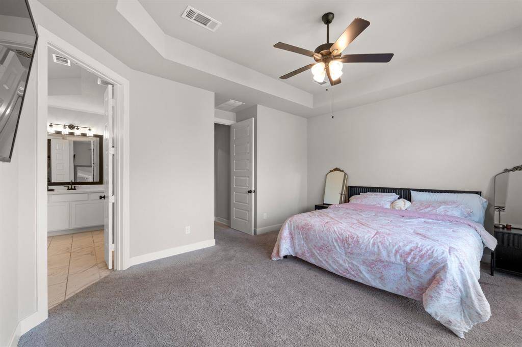 Primary bedroom retreat featuring tray ceilings, soft carpeting, and spacious layout.