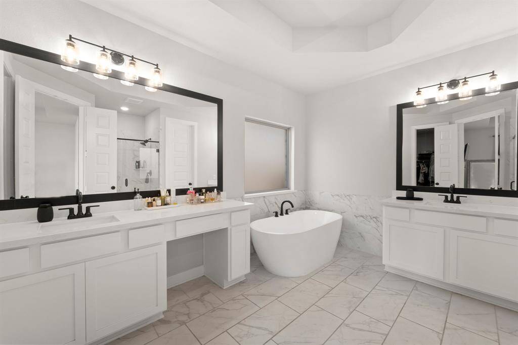Luxurious primary bathroom with double vanities, soaking tub, and elegant finishes.