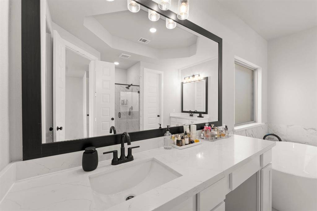 Dual vanity with framed mirrors and under-cabinet storage in the primary bathroom.