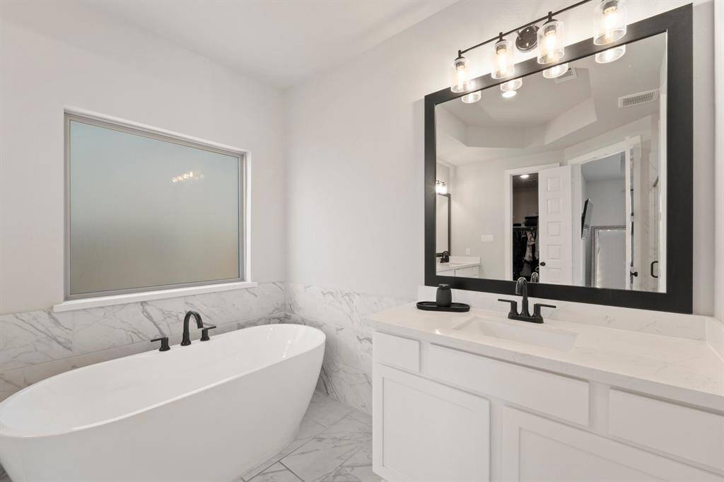 Secondary angle of primary bath with quartz counters and generous lighting.