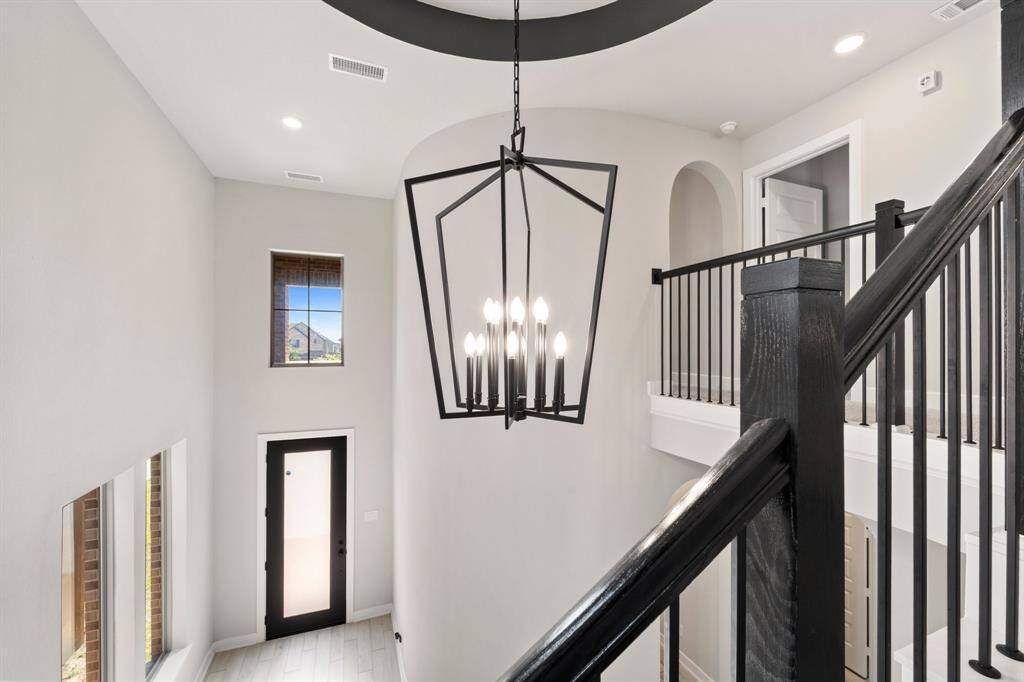 View from the landing with statement light fixture and elegant railing detail.