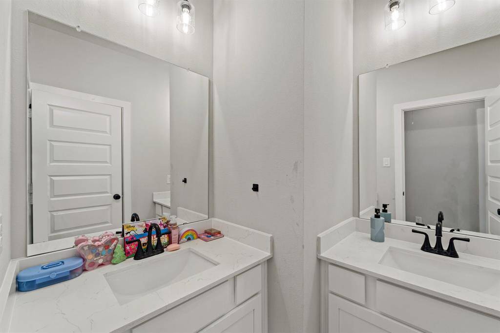 Full secondary bathroom with quartz countertop and modern lighting.