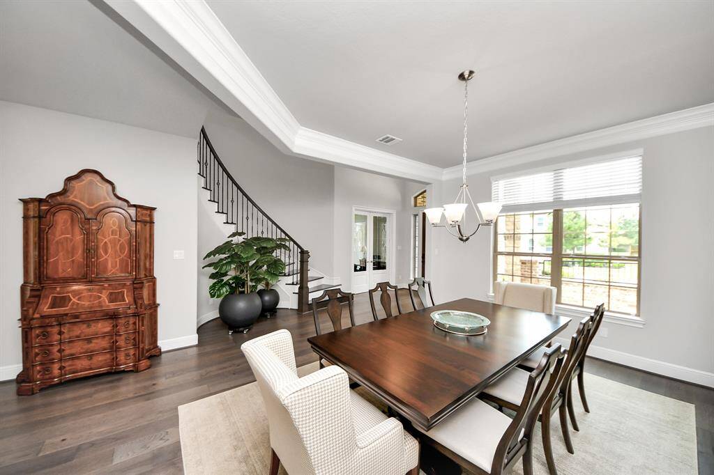 Elegant dining room with upgraded wood flooring and a large window overlooking the front patio.