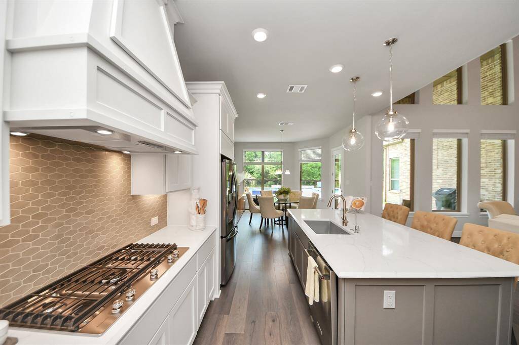 The kitchen is a chef's dream.  It features a 5-burner gas cooktop, stainless steel appliances, and ample natural light from large windows, leading to a cozy breakfast room.