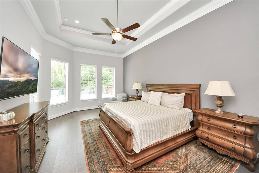 Discover a sunlit primary bedroom with spacious layout, perfect for a relaxing sitting area to unwind over looking the resort-like backyard.