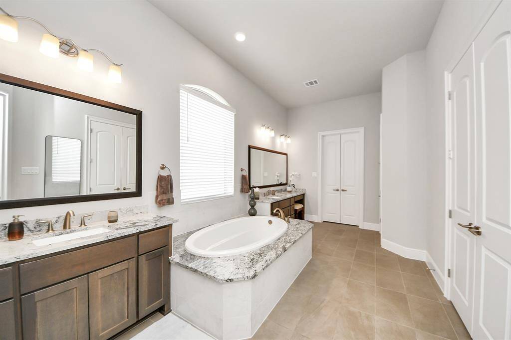 Primary bathroom includes a large window with blinds, a double-sink vanity, and modern fixtures, creating a bright and relaxing atmosphere.