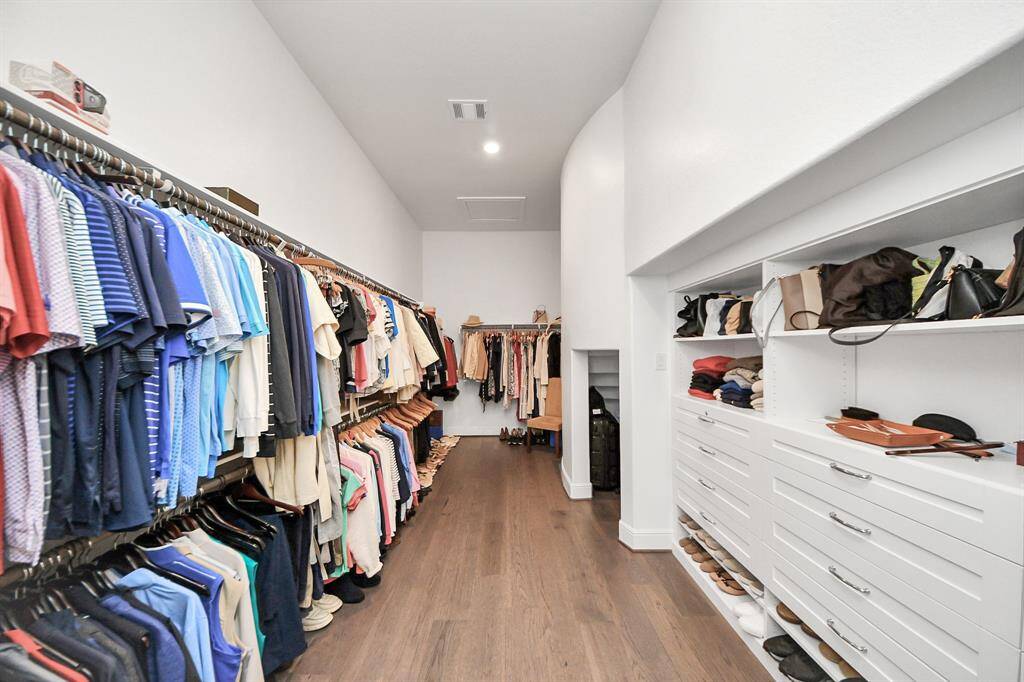 Spacious primary bedroom closet with built-ins and a dedicated luggage storage area.