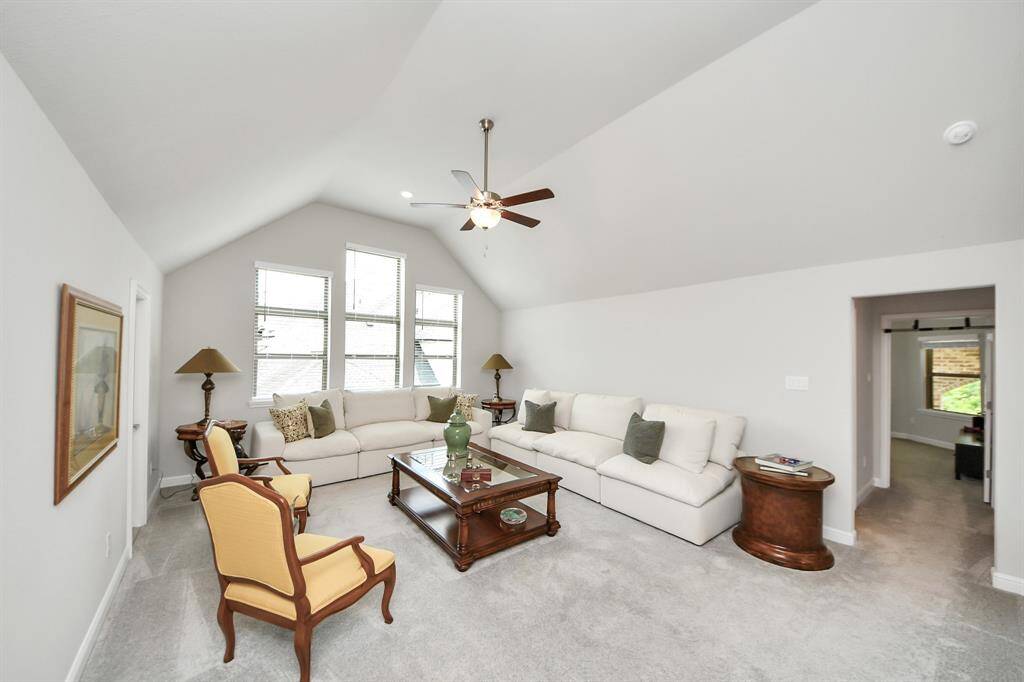 This spacious family room/game room features a high vaulted ceiling and ample natural light from three large windows.  The open doorway leads to a secondary bedroom.